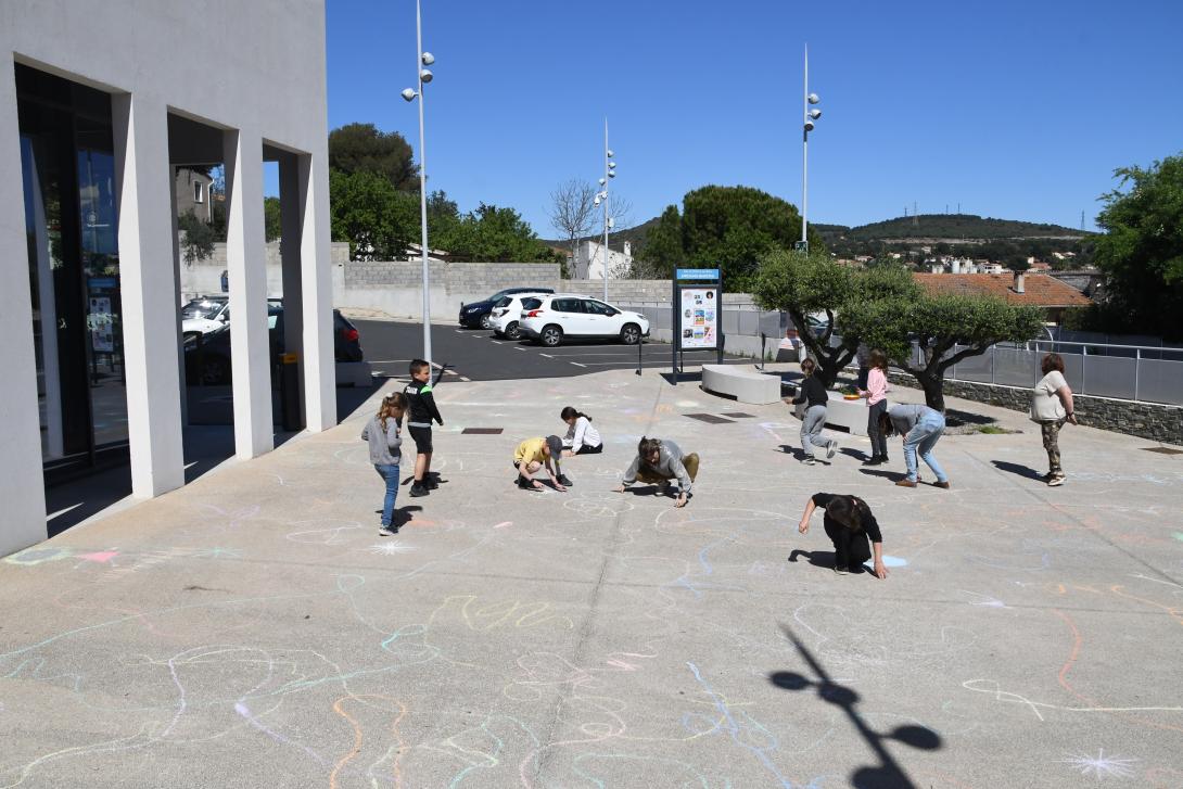 Les enfants dessinent sur le parvis sous le regard attentif de l'artiste Grâce Pégéron